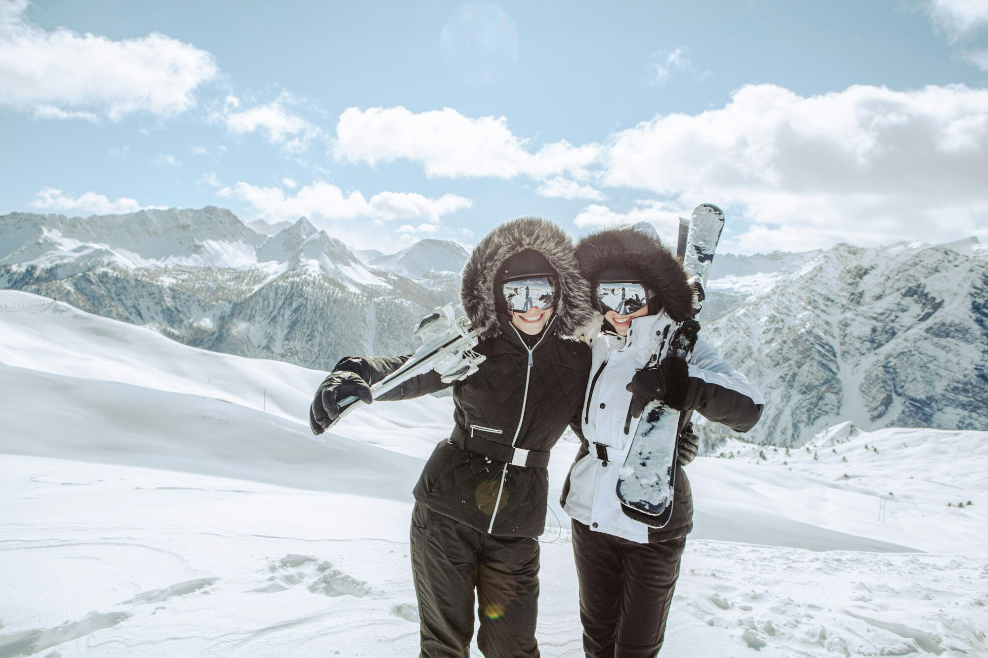 Deux clientes complices, skis à l'épaule, sommet enneigé