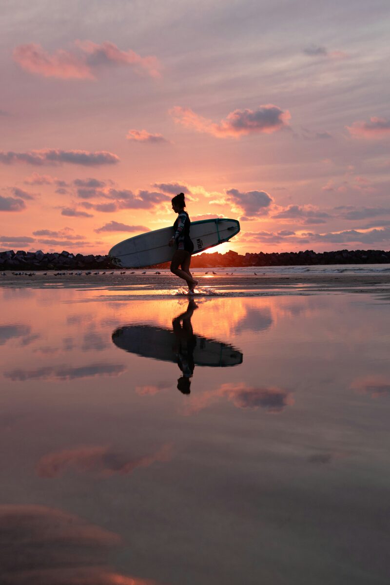 Jeune surfeuse au coucher du soleil, planche sous le bras